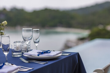 Blue and Silver Romantic Wedding Table Top Layout Table Spread no people catering, event, decor in a tropical location with the sea and clouds in the background