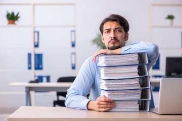 Young male employee and too much work in the office