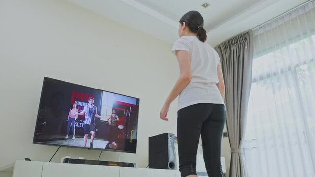 Active girl aerobic workout at home follow fitness execise video on TV