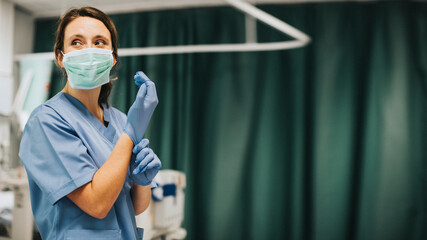 Fototapeta na wymiar Female nurse with a mask putting on gloves preparing to cure coronavirus patient
