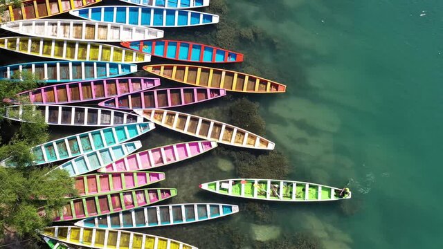 Colourful boats parking in Tamasopo River, San Luis Potosi, Mexico. Green river flowing in a mountain valley. Aerial view