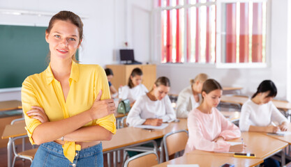 Attractive young female student standing in classroom full of students