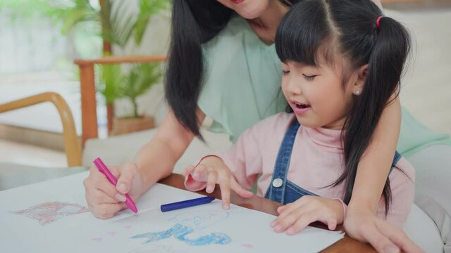 Mother teach and play with daughter paint and draw picture on paper.