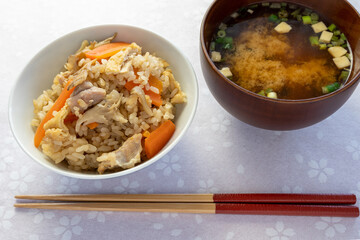 日本の家庭料理。舞茸ご飯と豆腐の入った味噌汁がピンク色の桜の花柄のテーブルに並んでいます（斜め上から撮影）