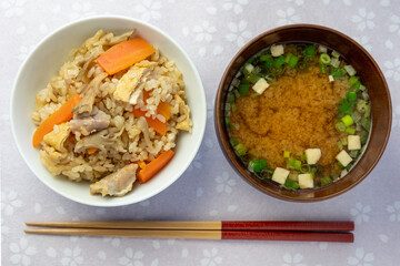 日本の家庭料理。舞茸ご飯と豆腐の入った味噌汁がピンク色の桜の花柄のテーブルに並んでいます（俯瞰撮影）