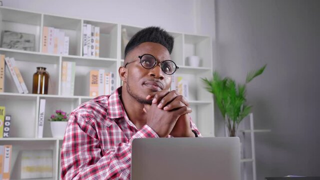 African man sitting in working room at home working and thinking to get solution on laptop, feeling stressed and tired. working alone, working from home concept