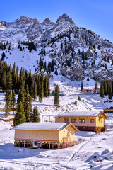 Mountain huts at the foot of rocky peaks in winter season