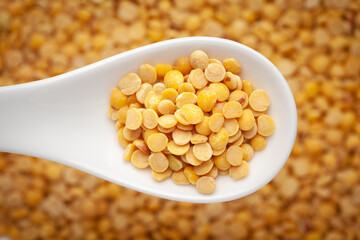 Macro Close-up of Organic arhar dal (Cajanus cajan) on a white ceramic soup spoon in a blurred background. Top view