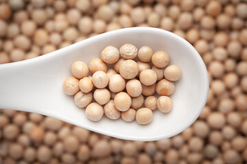 Macro Close up of Close up of Organic dry peas whole (Pisum sativum) or matar dal on a white ceramic soup spoon in a blurred background. Top view