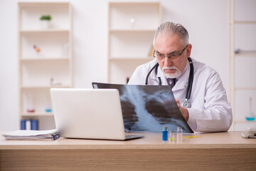 Old male doctor radiologist working in the clinic during pandemi