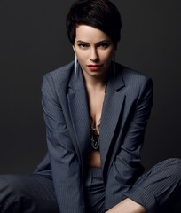 Attractive short haired brunette woman in business smart casual suit and earrings sitting looking...