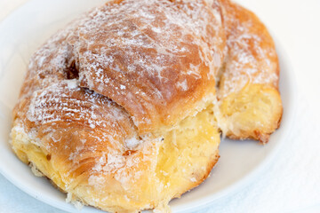 Typical Italian breakfast croissant, or cornetto / cornetti, with  jam filling served on a small plate on white table.