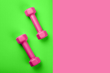 Top view of green sport mat and pink dumbbells neon pink background or set for pilates or fitness practice with copy space. Flat Lay.