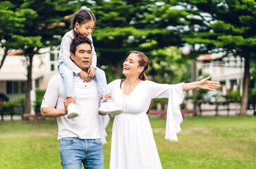 Portrait of enjoy happy love asian family father and mother holding cute little asian girl child smiling playing and having fun moments good time in summer park at home