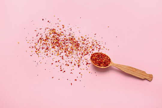 Spoon with ground chili pepper on color background
