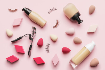 Makeup sponges with tonal foundation and eyelash curler on color background