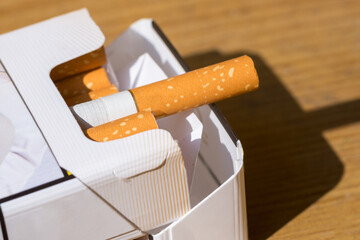 Open pack of cigarettes on old wooden table.Closeup pile cigarettes on a yellow table.