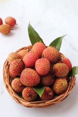 Bunch of fresh ripe lychee fruit with green leaves on white background. Exotic or tropical litchi fruit. Lichi. Copy space.