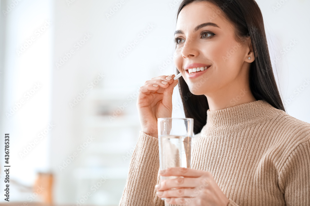 Wall mural beautiful young woman taking pills at home