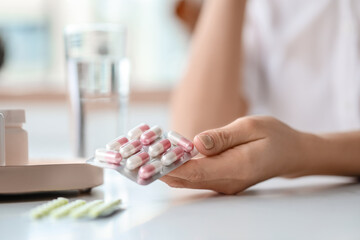 Obraz na płótnie Canvas Beautiful young woman taking pills at home, closeup