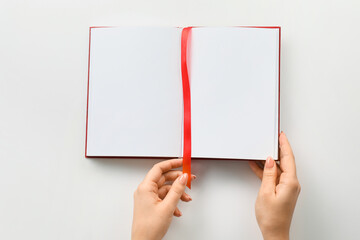 Female hands and blank book with bookmark on white background