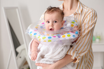 Woman and cute baby with inflatable ring at home