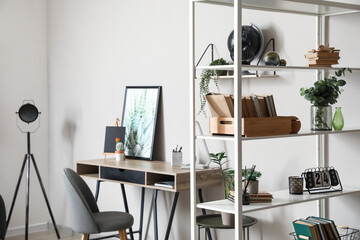 Modern workplace and book shelf near light wall