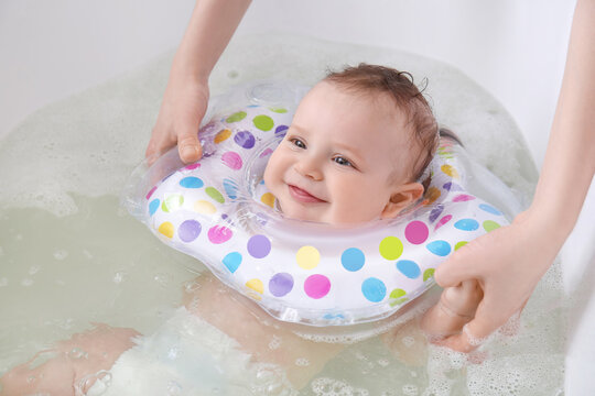 Mother and cute baby with inflatable ring in bathroom