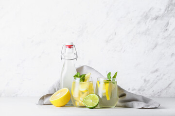 Bottle and glasses of tasty cold lemonade on light background