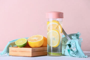 Bottle of tasty cold lemonade on color background