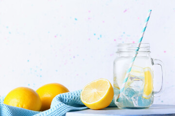 Mason jar of tasty cold lemonade on light background