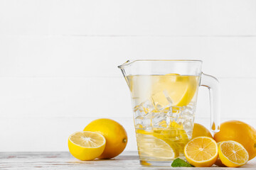 Jug of tasty cold lemonade on light background