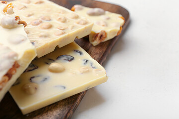 Pieces of sweet white chocolate on light background