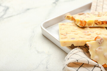 Tray with pieces of white chocolate on light background