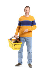 Young man with shopping basket on white background