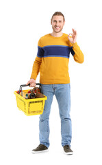 Young man with shopping basket on white background