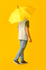 Handsome young man with umbrella on color background