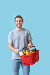 Fototapeta na wymiar Young man with shopping basket on color background