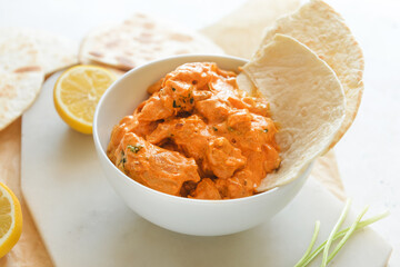 Bowl of tasty chicken tikka masala on table