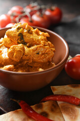Bowl of tasty chicken tikka masala on table
