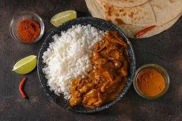 Bowl of tasty chicken tikka masala and rice on dark background