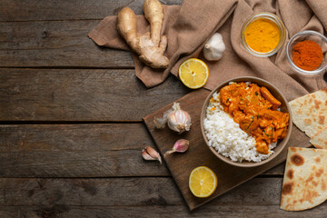 Bowl of tasty chicken tikka masala and rice on table