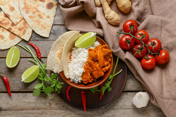 Bowl of tasty chicken tikka masala and rice on table