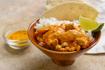 Bowl of tasty chicken tikka masala and rice on grey background
