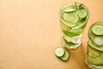 Glasses with cucumber lemonade on color background