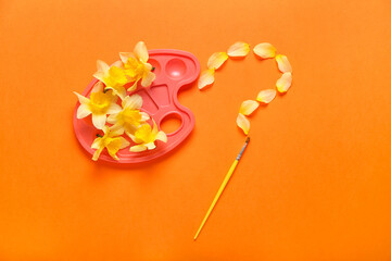 Creative composition with beautiful daffodils, paint brush and palette on color background