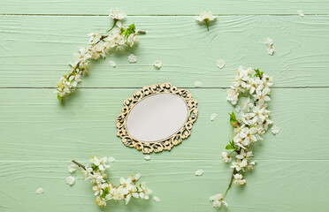Beautiful blooming branches and blank card on color wooden background