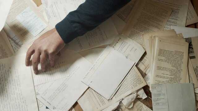 Male hands nervously searching old documents. Top shot.
