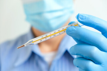 Doctor holding human body temperature thermometer to measure the fever at 37.5 degrees.
