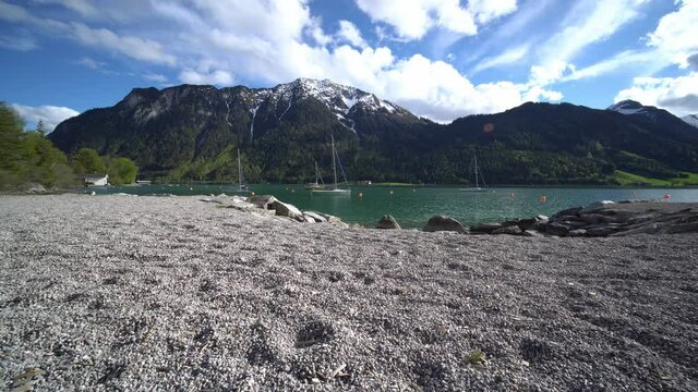Boats on lake in mountains, clouds and blue sky in Austrian Alps